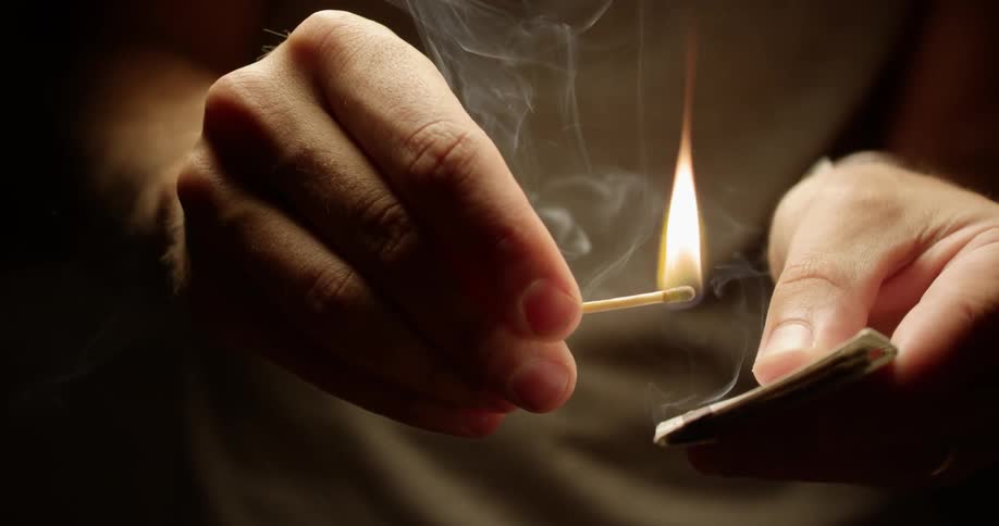 A man's hands lighting a match from a matchbook