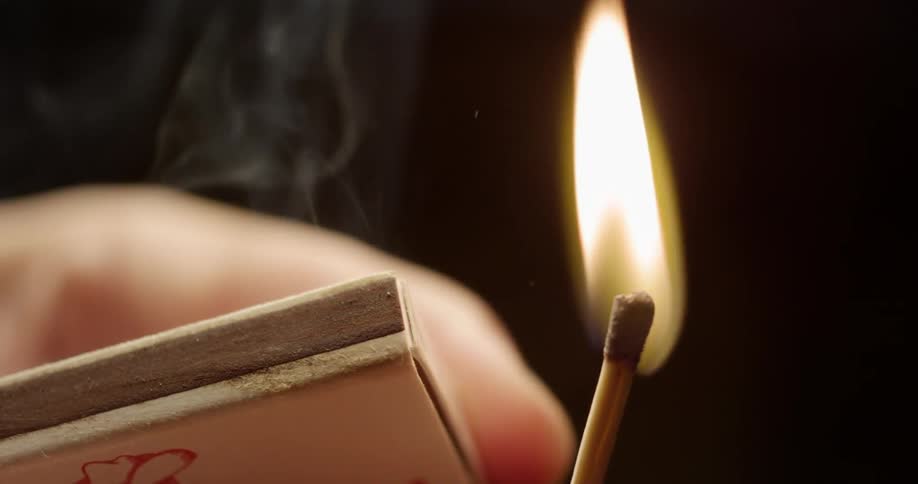 A match is struck and lit on the side of a matchbox