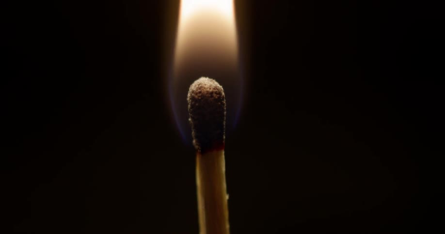 A burning match sets another match ablaze