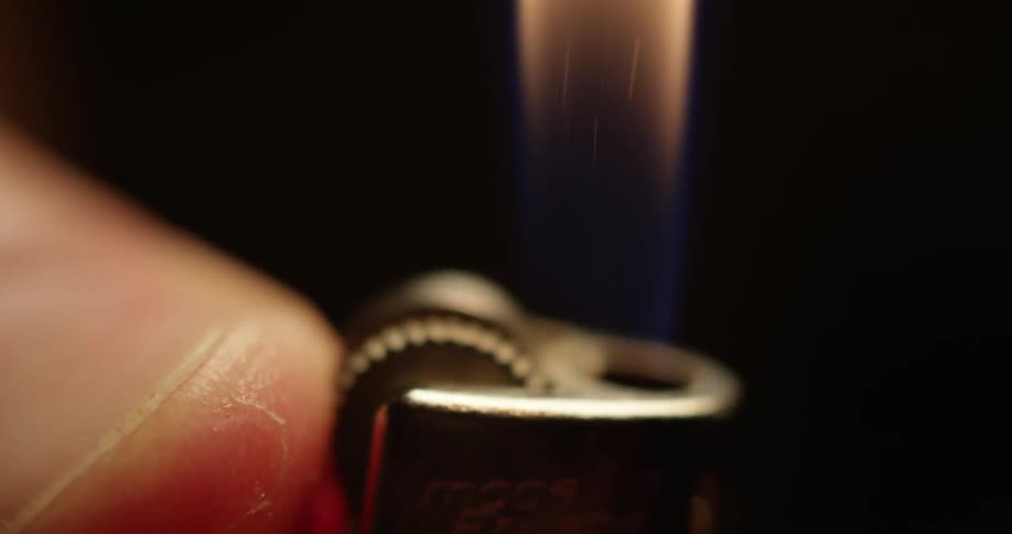 A lighter is lit with a thumb