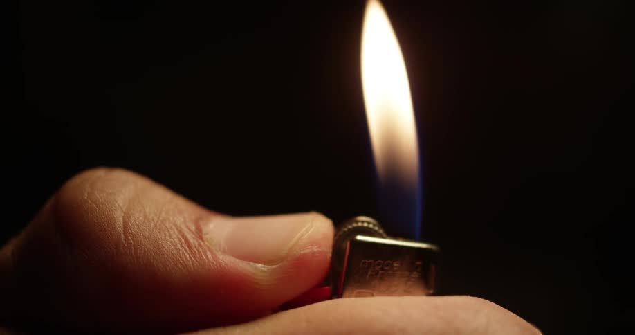 A person turns on a lighter and the flame burns