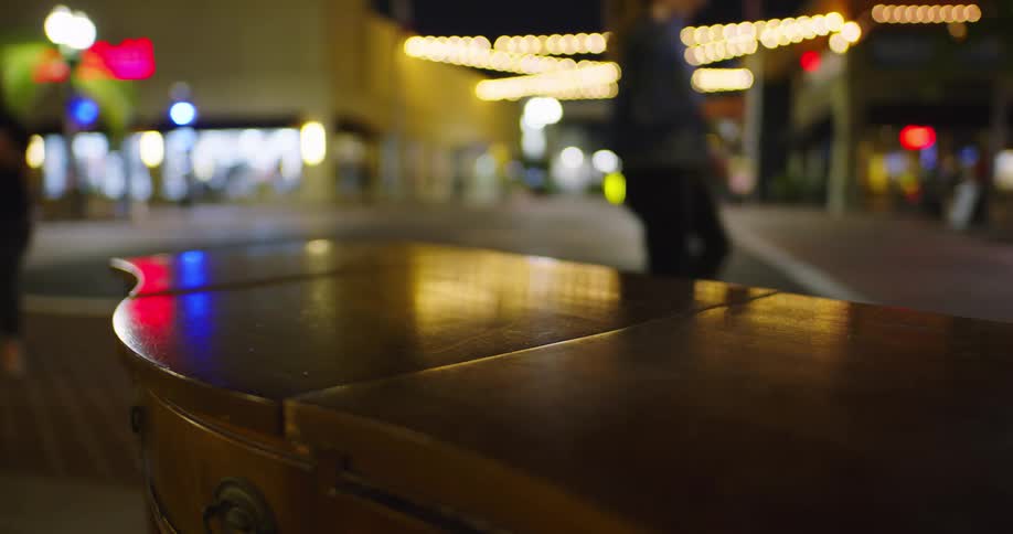 A piece of furniture sits on a city street as people walk by and cars drive past