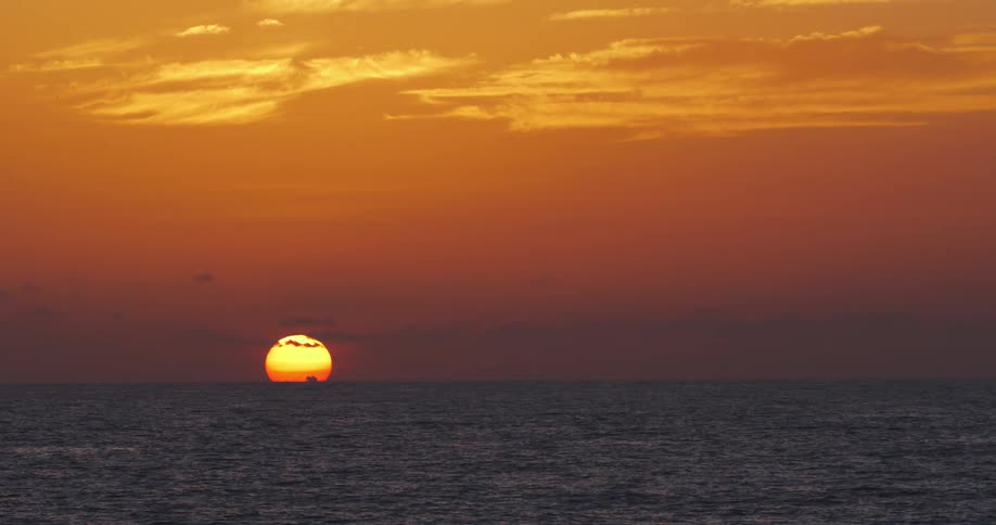 The sun is setting above the ocean water