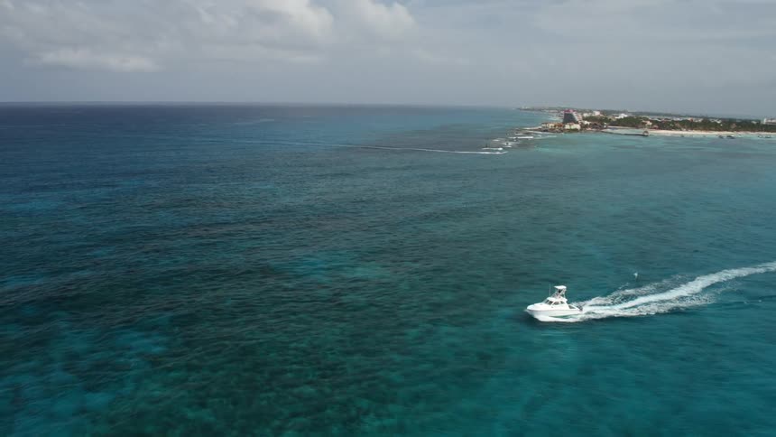 A boat sails on turquoise ocean waters off the coast