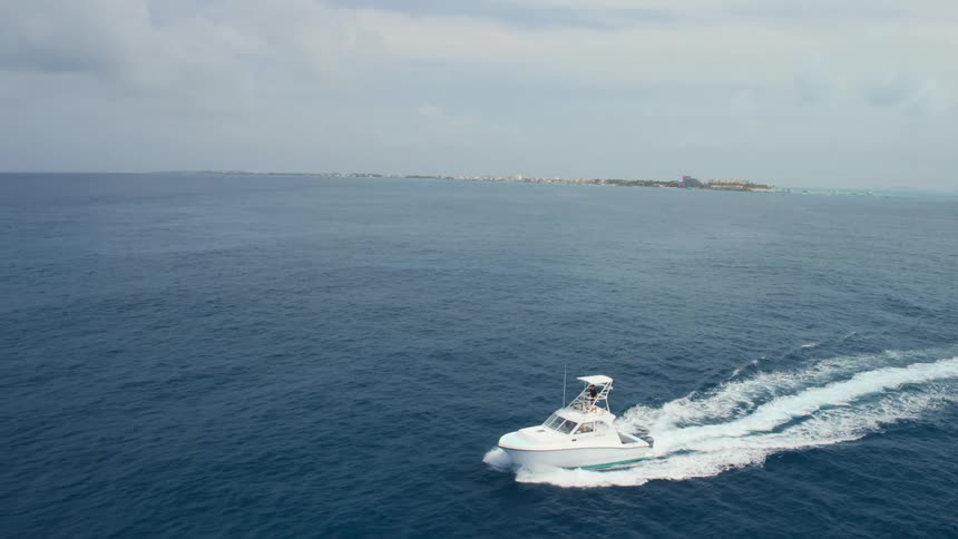 An aerial view of a boat sailing on blue ocean waters