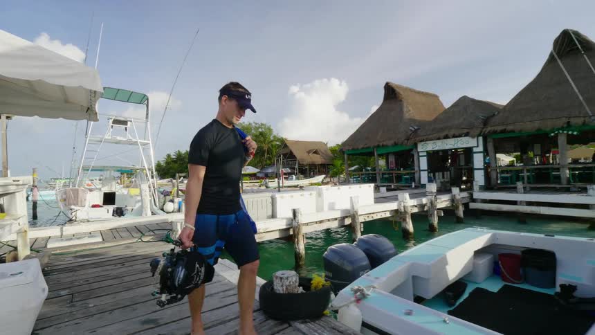 A man walks off the docks to load his boat with a camera