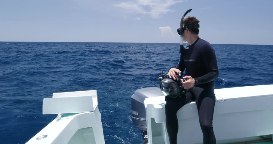 A man is riding a boat in the ocean with scuba gear on