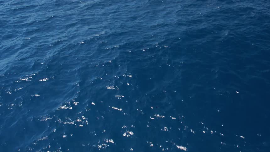 An aerial view of blue ocean water on a sunny day