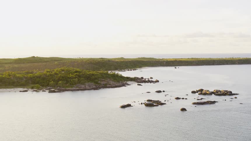 Aerial view of rocks and promontories in front of the coast of an island at sunset