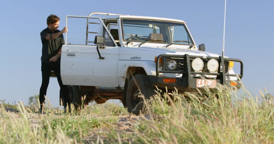 Man exits a vehicle then a dog jumps out of the vehicle too