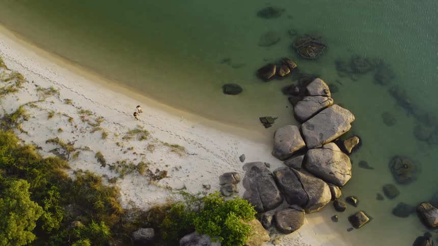 Aerial view of two people walking on the shore