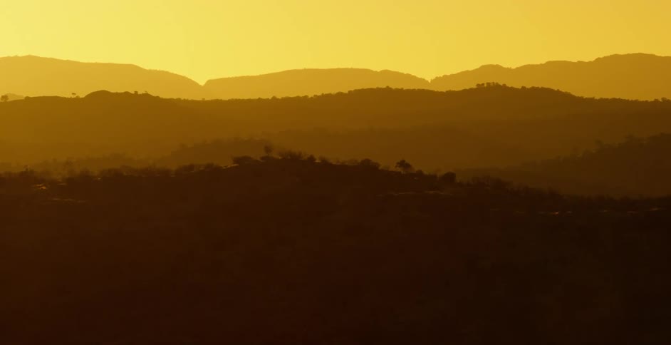 Forest and mountains sit as the sun rises at dawn