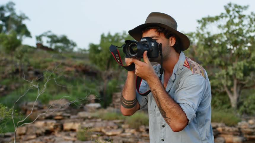 A man is taking photos with a camera outdoors