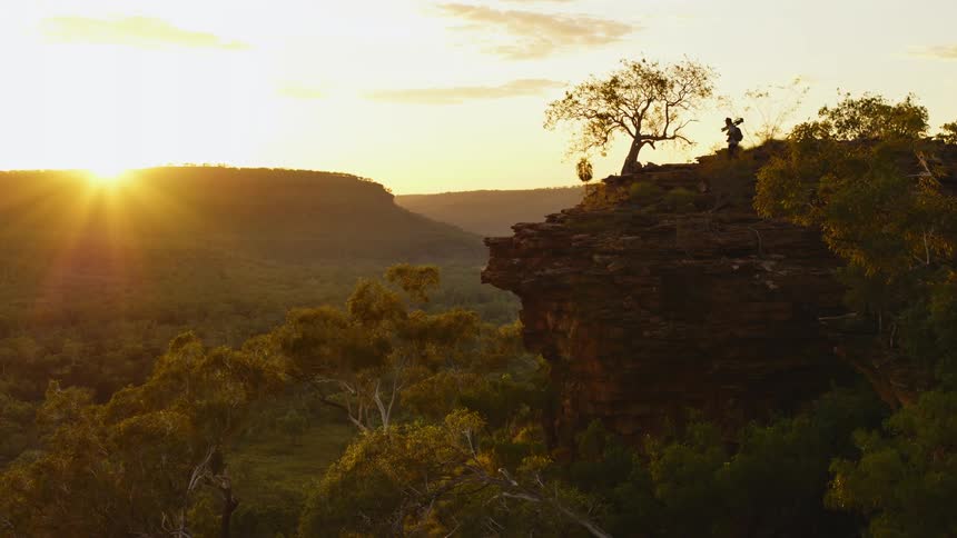 A man carries his camera to the cliff