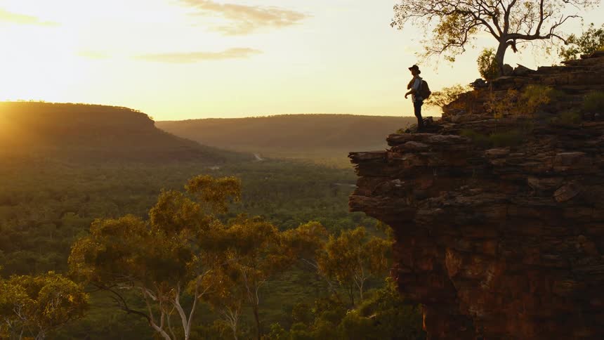 A man is standing outdoors at sunset