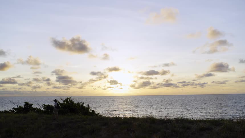 Silhouette of a man walking on the coast near the ocean at sunset