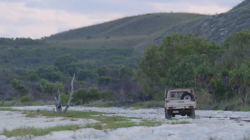 All terrain vehicle driving over sand near the mountains
