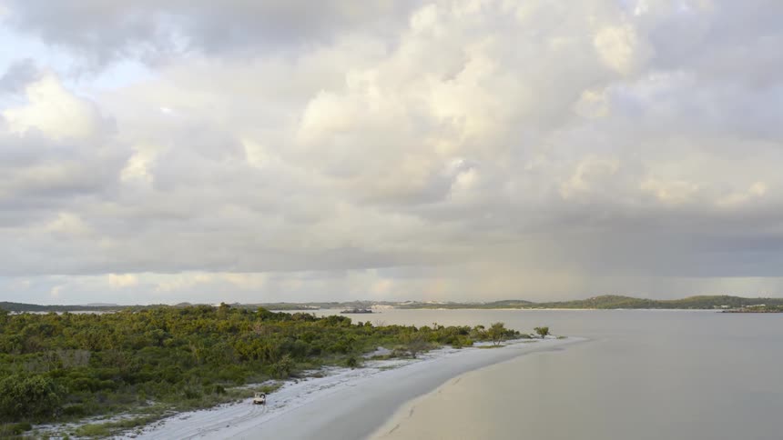 A vehicle is driving around the shore of the island