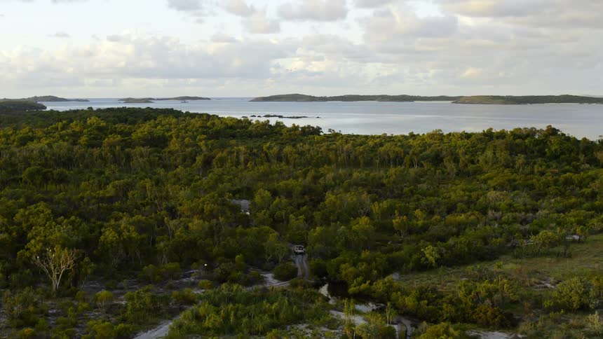 An aerial view of a vehicle driving on a beach road