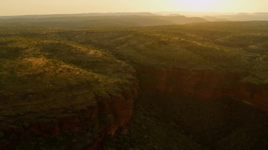 An aerial view of the sun setting over a rocky cliff