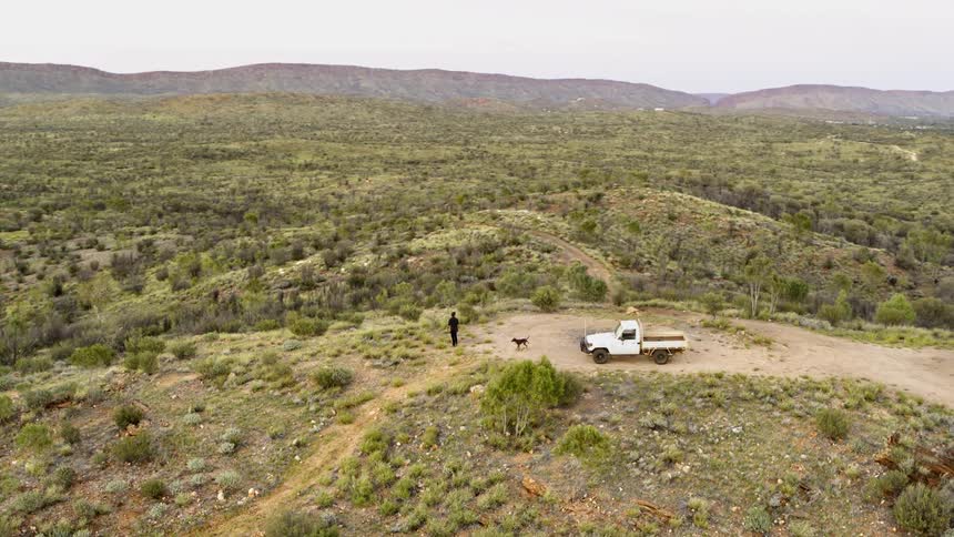 A person walks from their truck that is parked in the middle of a sprawling desert area