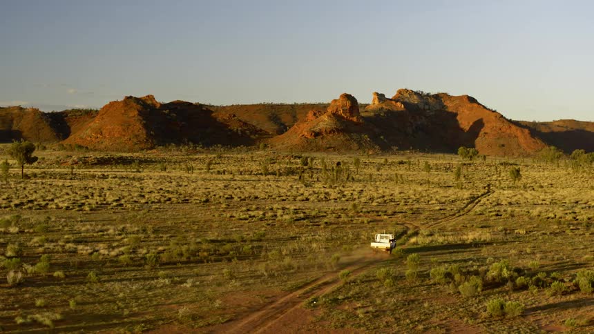 A white truck drives off road near mountains in nature