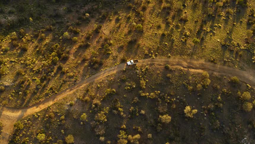 A truck travels along a dirt road through a grassland