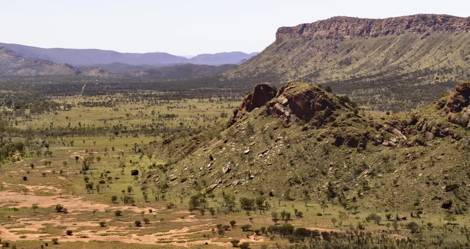 Aerial view of a rock promontory in the plains near a mountain range