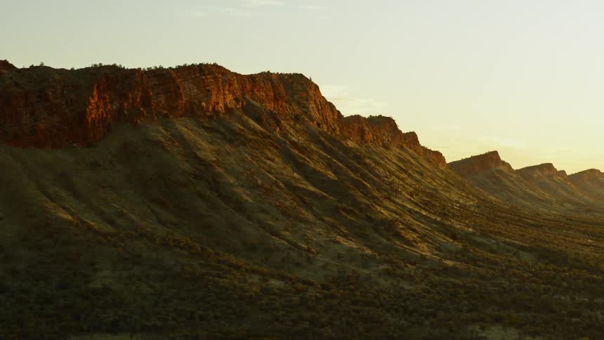 Brush covered red rock mountains during sunrise