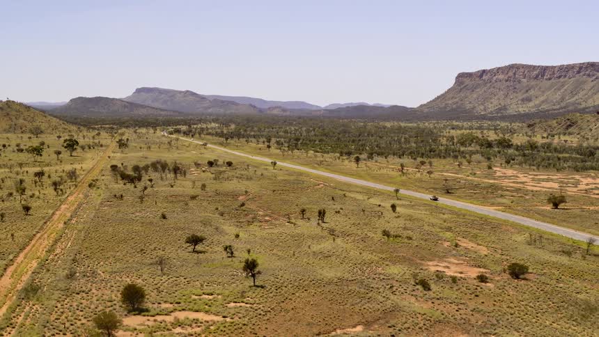 Aerial view of a car driving on a road in a large area of land