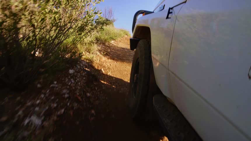 A vehicle is driving uphill in a rural area
