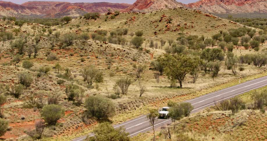 White pickup truck drives on a highway seen from a hill