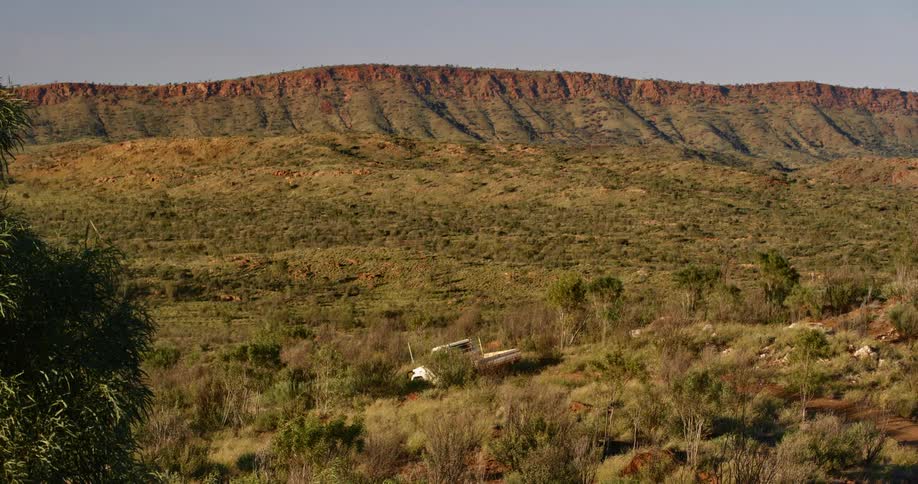 White truck drives on a dirt road through the shrubs near the mountains