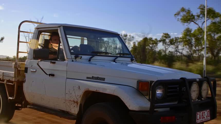 White pickup truck drives on a dirt road smoothly