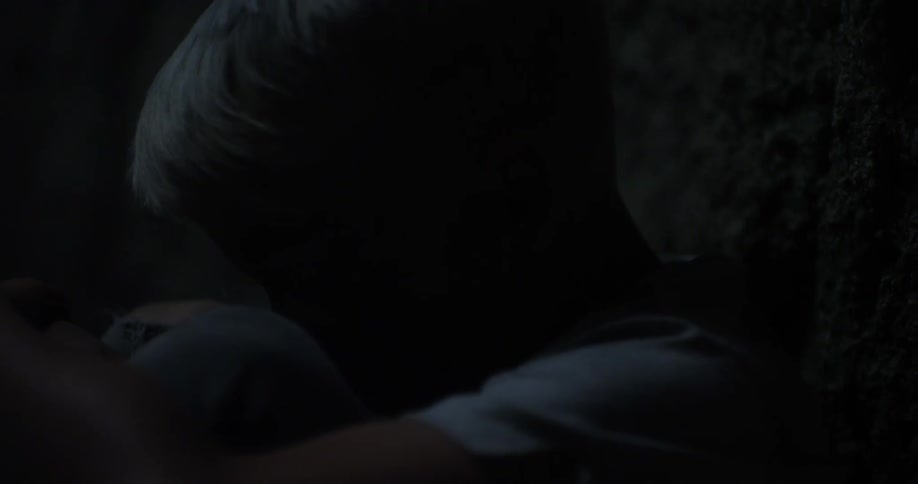 A frightened child hides his head in his knees in the dark