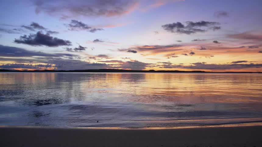Sunlight reflecting on the calm sea waters on a beach at sunset
