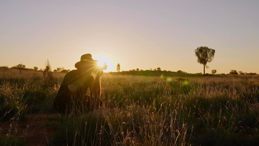 A man is taking photographs in the grass