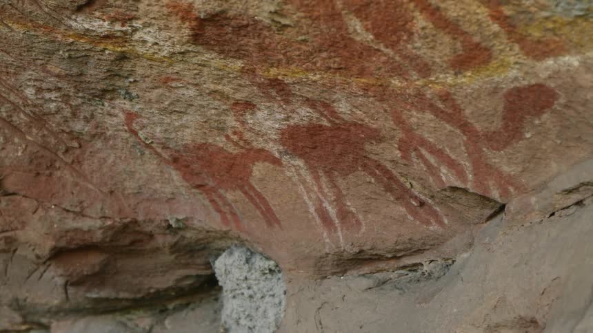 Red stains form the shape of animals on the side of a canyon