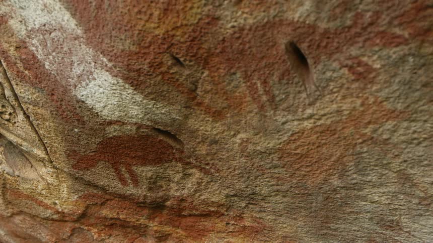 Animal shapes are painted in red on the side of a canyon