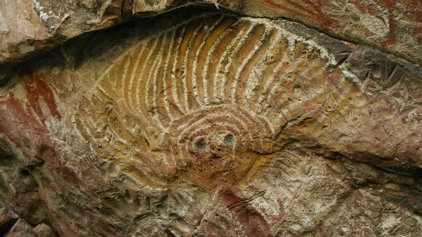 An intricate drawing that almost looks prehistoric is displayed on a rocky surface
