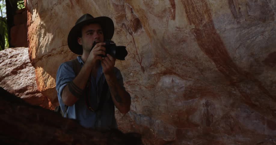 A photographing taking photographs of primitive wall paintings in the wilderness