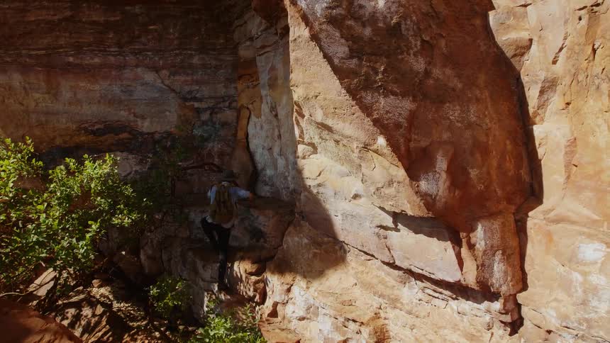 Man begins to climb up the side of a mountain