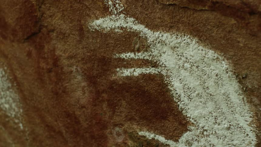 A white drawing of an animal covers a red rock