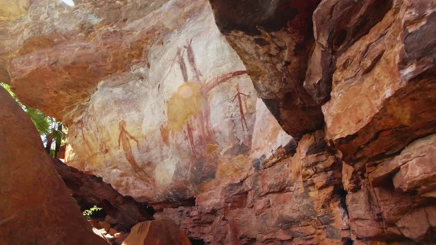 Cave paintings cover stone wall under overhang