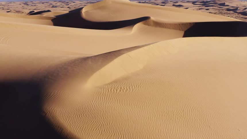 A desert with sandy dunes with the sky and clouds in the background