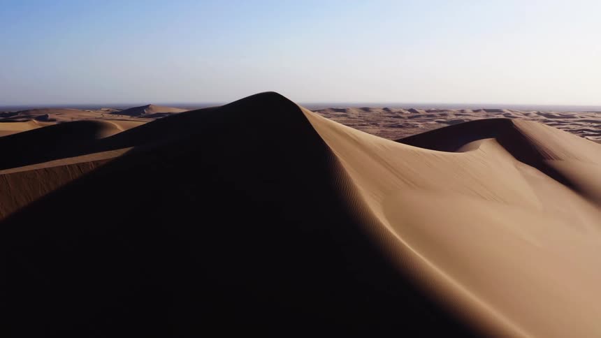 A desert with sandy dunes with the sky and clouds in the background