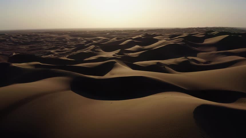 Sand dunes cover a desert landscape