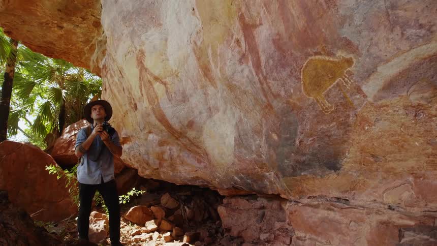 A man is taking pictures of a rock formation