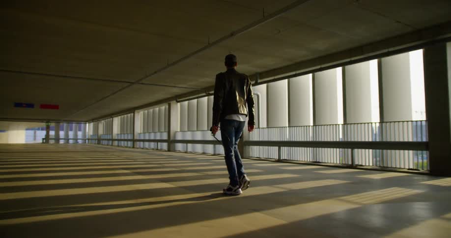A man is walking through the high rise parking lot