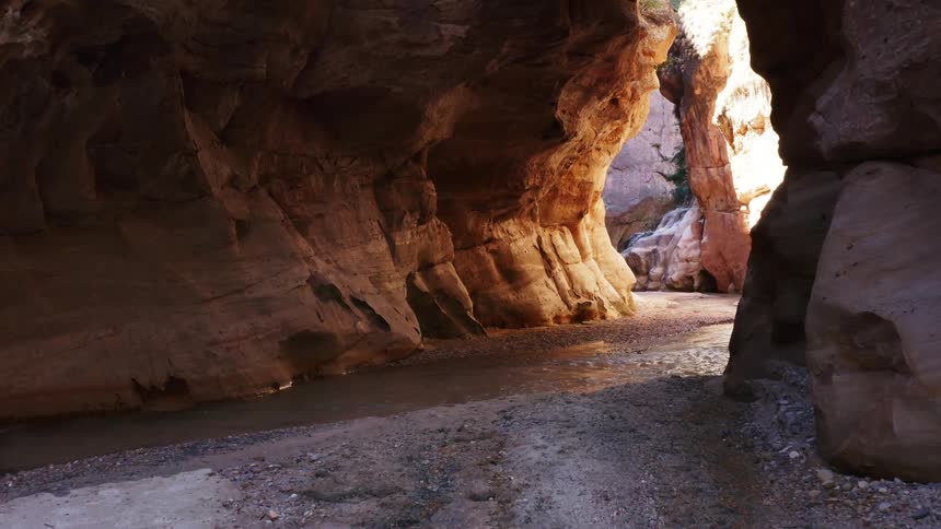 A stream flows throw red rock formations in a canyon